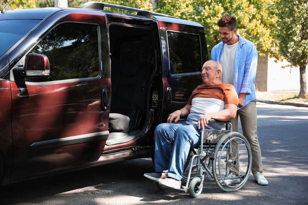 Support worker helping senior with mobility support to car